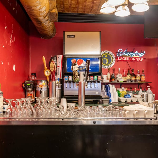 A bar area with red walls, various beer taps, soda fountain, and liquor bottles on shelves.
