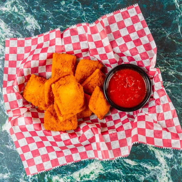 Crispy fried ravioli with a side of marinara sauce in a red and white checkered basket.